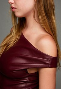 Bordeaux off-shoulder top van glad leer, met een asymmetrisch ontwerp, een aangesloten silhouet en zonder mouwen.