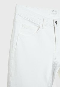 Jeans in denim bianco con un classico design a cinque tasche, leggera texture e una tradizionale chiusura con bottone e zip, con un bottone in metallo nero.