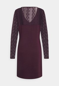 Robe violette foncée jusqu'aux genoux avec manches longues en dentelle transparente et décolleté en V en dentelle.
