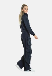 Marintröja med en åtsittande hoodie med hög krage och cargobyxor med flera fickor, tillverkad av ett mjukt, stretchigt tyg.