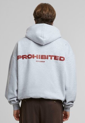 Sudadera gris con un gran texto rojo "PROHIBIDO" en la parte posterior, acompañado de "10119, BERLÍN." Corte holgado y tejido suave y texturizado con capucha.