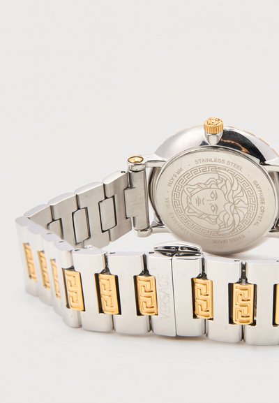 Μεταλλικό λουράκι ρολογιού σε ασημί και χρυσό με χαραγμένο το κεφάλι της Μέδουσας στην πίσω πλευρά από ανοξείδωτο ατσάλι και το λογότυπο της Versace στο κούμπωμα.