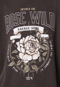 Grafický tričko v tmavě hnědé barvě s bílou a béžovou ilustrací růže, tučným textem a vintage akcenty. Obsahuje rok 1974.