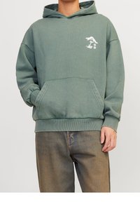 Vihreä huppari, joka on valmistettu pehmeästä kankaasta. Siinä on etutasku, resorit helmassa ja hihoissa. Rinnan alueella valkoinen graafinen kuvio.