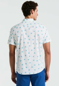 Korte mouwen, wit shirt met een herhalend blauw bladerenpatroon, button-down kraag en een gebogen zoom. Lichtgewicht stof met een ontspannen pasvorm.