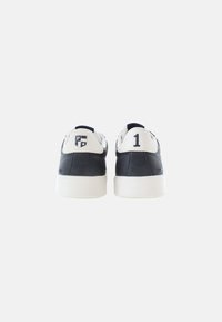 Námořnické kožené tenisky s bílými detaily, které mají na patě logo a číslo "1". Ploché gumové podrážky a zaoblený design špičky.