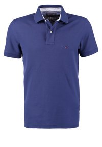 Polo bleu marine à manches courtes avec doublure blanche à l'intérieur du col et petit logo Tommy Hilfiger sur la poitrine gauche.