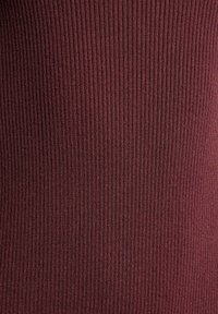 Burgundská žebrovaná látka, texturovaná vertikálními pruhy, vykazuje elasticitu a hladký povrch. Bez viditelných vzorů nebo dalších detailů.