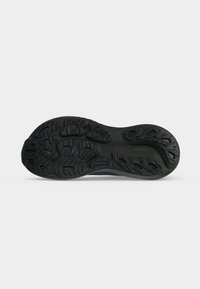 Sole of black Brooks running shoe showing detailed textured tread pattern and brand name on gray background.