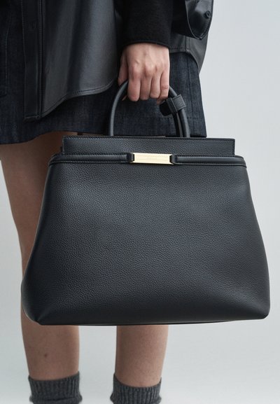 Mustat nahkalaukut, joissa on jämäkkä muoto, sileä pinta ja kultaiset yksityiskohdat. Varustettu kahdella kantokahvalla.