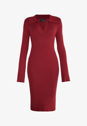 Czerwona, prążkowana sukienka z długim rękawem, głębokim dekoltem w kształcie litery V i kołnierzykiem. Dopasowany krój, sięgająca do połowy łydki, gładka faktura i bez widocznych zapięć.