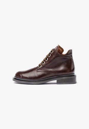 Bruine leren enkelboots met een gladde textuur, ronde neus, zes gouden oogjes en een contrasterende bruine tong, geplaatst op een stevige zwarte zool.