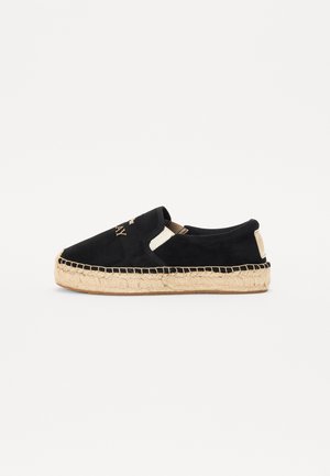 Sort slip-on espadrille med beige vævet juttesål og syningsdetaljer, med guldbogstaver på overdelen.