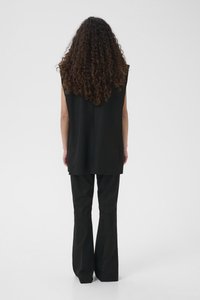 Mustast hõlmikuta topist, millel on lõdvestunud lõige ja seljasaum, kombineeritud mustade lehvikpükstega, millel on sile pind ja nähtamatud kinnitused.