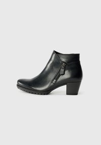 Svarta ankelstövlar med en stilren design, med en sidodragkedja och en diskret klack, vilande mot en enfärgad vit bakgrund.