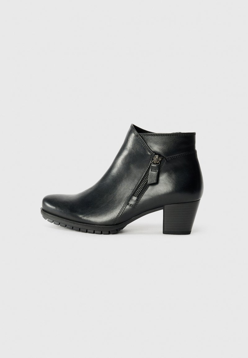 Svarta ankelstövlar med en stilren design, med en sidodragkedja och en diskret klack, vilande mot en enfärgad vit bakgrund.