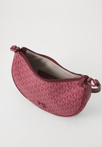 Porte-monnaie en tissu à motifs rouges avec une fermeture éclair, de forme courbée et un intérieur lisse. Il comprend un logo et des accents de quincaillerie assortis.