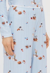 Lyst blå pyjamas sæt med ribbet tekstur, prydet med et madmønster af croissanter, pandekager og kaffekopper. Accentueret med blonder.