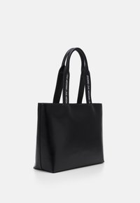 Schwarze Leder-Tote-Tasche in rechteckiger Form, mit zwei flachen Griffen, die Text tragen, und glatter Textur. Minimalistisches Design ohne zusätzliche Akzente.