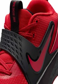 Punainen urheilukenkä, jossa on verkkomainen päällinen, pehmustettu kaulus, musta muovinen tukikerros ja sivussa heijastava logo.