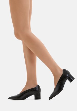 Décolleté in vernice nera con punta appuntita e tacco medio a blocco. La texture presenta un delicato motivo coccodrillo.