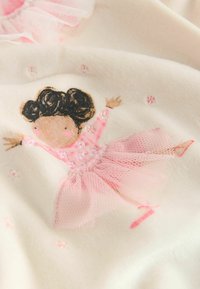 Weicher cremefarbener Stoff mit einer Illustration eines Mädchens in einem rosa Kleid mit Tüllrock, gestickten Details und verstreuten Blumenakzenten.