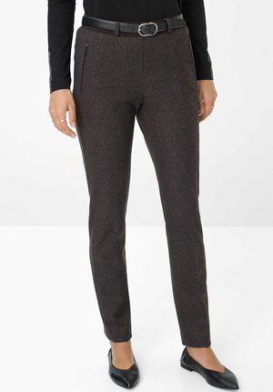 Eng anliegende dunkelbraune, strukturierte Hose mit seitlichen Reißverschlusstaschen, kombiniert mit einem schwarzen Gürtel, schwarzen spitzen Ballerinas und einem schwarzen Langarmoberteil.