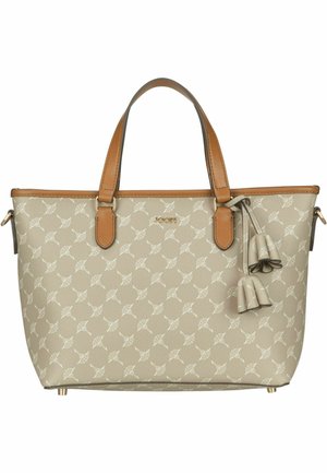 Sac fourre-tout beige avec un motif léger de feuilles, anses en cuir marron, pompons décoratifs et logo doré centré près du bord supérieur.