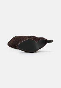 Stivale marrone in suede sopra il ginocchio con punta affilata e suola in gomma texturizzata. Presenta una silhouette elegante e un design da infilare.