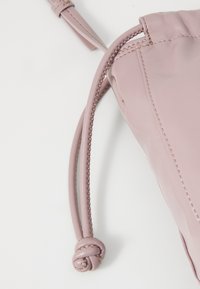 Borsa rotonda in pelle rosa con una finitura testurizzata, dotata di un cordino intrecciato e di un dettaglio di nodo sicuro su un lato.