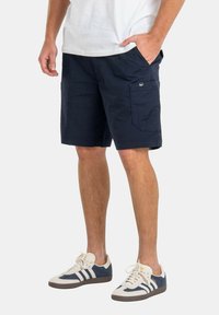 Bermudas de carga azul marino con bolsillos frontales y laterales, un corte relajado, hechas de tejido transpirable, y con una pequeña etiqueta de logo en el costado.