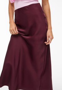 Keskitason tumman viininpunainen satiinihame, jossa on sileä pinta ja hieno kiilto, ja sivuaukko lisäämään liikettä.