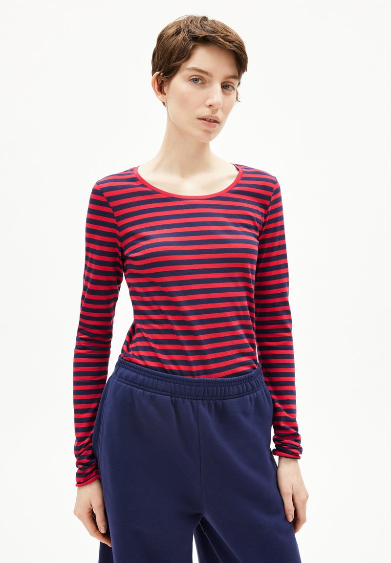 Langärmliges T-Shirt in rot und marineblauen horizontalen Streifen, mit Rundhalsausschnitt und tailliertem Design, kombiniert mit marineblauen Hosen.