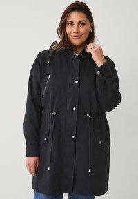Zwarte hooded jack met elastische trekkoorden in de taille, zijzakken en een ritszak op de borst, gemaakt van lichtgewicht stof.