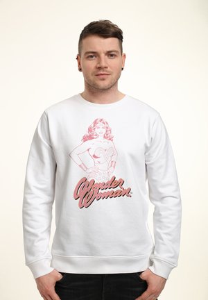Weißer Pullover mit einem pinken Grafikdesign von Wonder Woman, darunter ihr Name in fetter Schrift. Lässiger Schnitt, runder Halsausschnitt, gerippte Bündchen.
