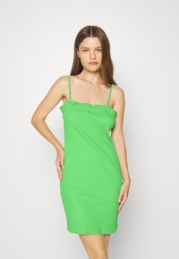 Vestido midi verde com textura canelada, alças finas ajustáveis e detalhe de decote com babados. Silhueta ajustada com uma textura suave.