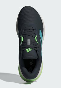 Baskets de sport noires avec une tige texturée, des accents verts et bleus, et une semelle rembourrée. Comprend des lacets et un col rembourré.