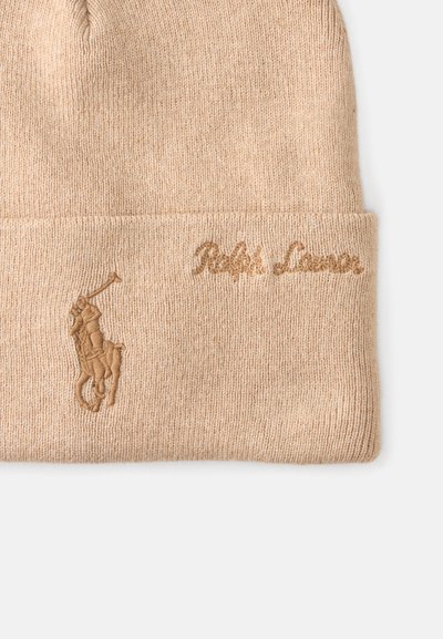 Bežinė megzta kepurė su sulenktu kraštu, puikuojanti siuvinėjimu polo žaidėjo logotipu ir "Ralph Lauren" atitinkančios spalvos siūlais.
