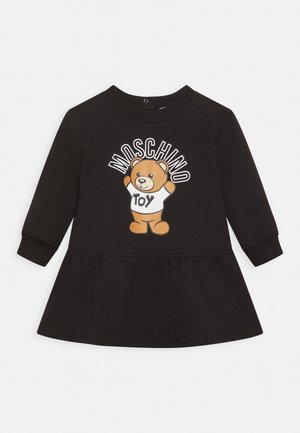 Schwarzes Langarmkleid für Kleinkinder mit Rüschensaum, das einen Teddybären zeigt, der ein "TOY"-Shirt trägt, und darüber steht "MOSCHINO".