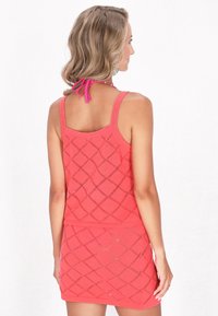 Set di top e gonna lavorato a maglia rossa con un motivo a diamante, spalline regolabili e una texture liscia. La vista posteriore mostra capelli raccolti con un'accento legato.