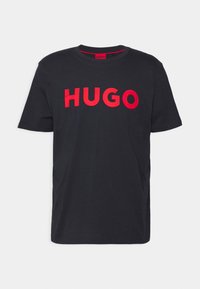 Černé bavlněné tričko s výrazným červeným nápisem "HUGO" na přední straně. Standardní kulatý výstřih a krátké rukávy. Hladká textura.