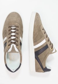 Baskets en daim marron avec des accents en cuir blanc et marine, dotées de panneaux texturés, d'un bout rond et de semelles en caoutchouc blanches.