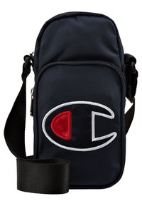 Granatowa torba na ramię z nylonu z regulowanym czarnym paskiem, z przodu znajduje się duże wyszywane logo w kolorach czerwonym i białym. Torba zamykana na zamek błyskawiczny.