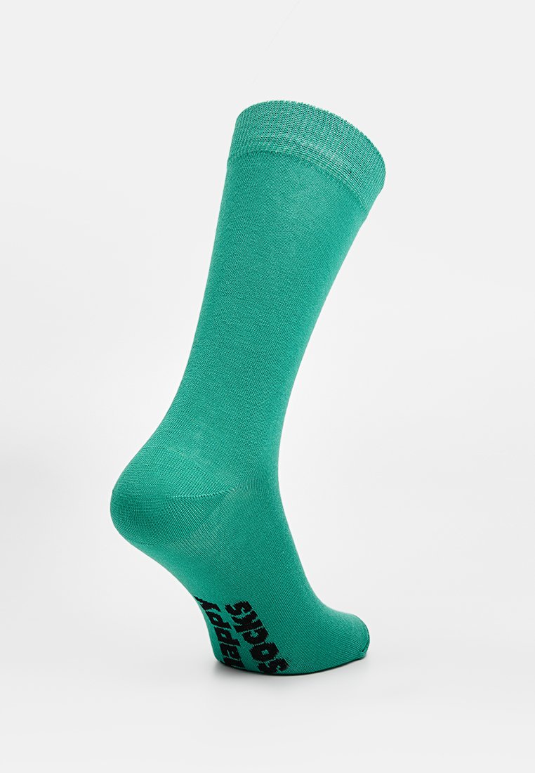 Turkusowa skarpetka bawełniana z prążkowanym mankietem, gładką strukturą i czarnym logo "Happy Socks" nadrukowanym na dolnej stronie.