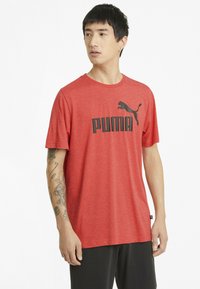 Červené tričko s krátkým rukávem vyrobené z měkkého materiálu, s černým logem "PUMA" a malým grafickým ztvárněním skákající pumy.
