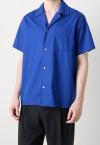 Niebieska koszula na krótki rękaw z guzikami, wykonana z lekkiego materiału, z kieszonką na piersi i klasycznym kołnierzem.