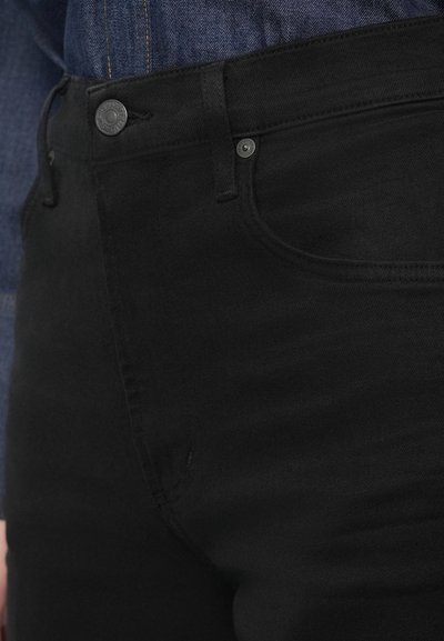 Čierne džínsové nohavice z denimu s priliehavým strihom, vybavené štandardným zapínaním na gombík a zips a jemnými švami.