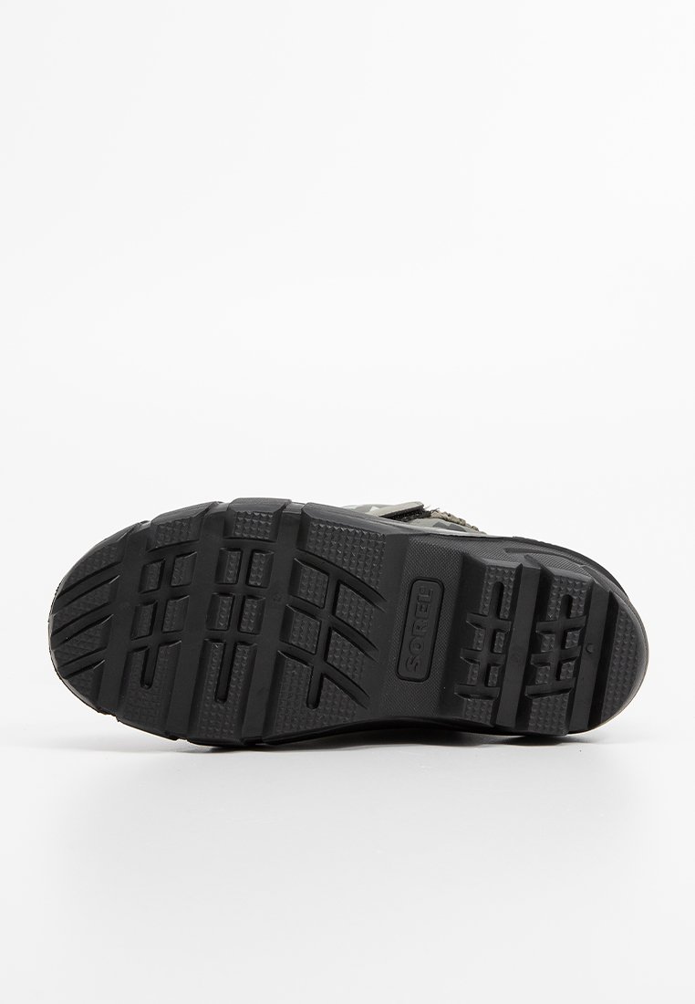 Czarna gumowa podeszwa z głębokim wzorem bieżnika, z teksturowanymi uchwytami i brandingiem. Trwała i solidna konstrukcja zapewniająca przyczepność i wsparcie.