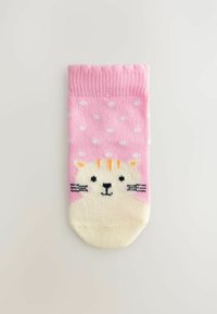 Chaussette rose avec des pois blancs, ornée d'un motif de visage de chat en crème avec des rayures orange. Fabriquée en matière tricotée douce.
