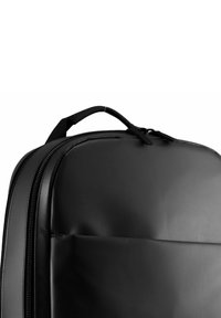 Schwarzer Rucksack mit glatter Oberfläche, runder Form, doppelten Reißverschlüssen und einem oberen Tragegriff für einfachen Transport, entworfen für Funktionalität.